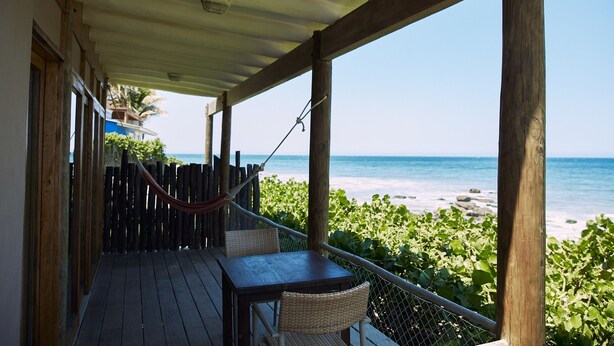 A wooden deck with a table and chairs overlooking a beach. - Cocaloba Adobe by Wynwood House (Máncora)