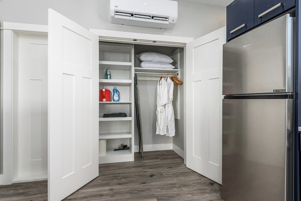 A walk-in closet with shelves, a hanging rack, and a built-in refrigerator.