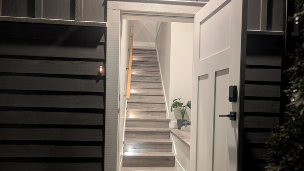 Een modern interieur met een houten trap die leidt naar een vloer met een deurmat.
