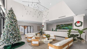 A modern lobby with a large Christmas tree, comfortable seating, and a reception desk. - Sleep 6 in Resort Style Community- Near Stadium (North Miami)