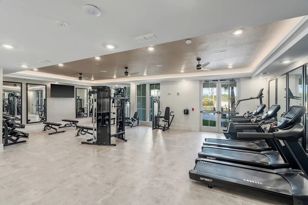 A modern gym with treadmills, weight machines, and a mirrored wall.