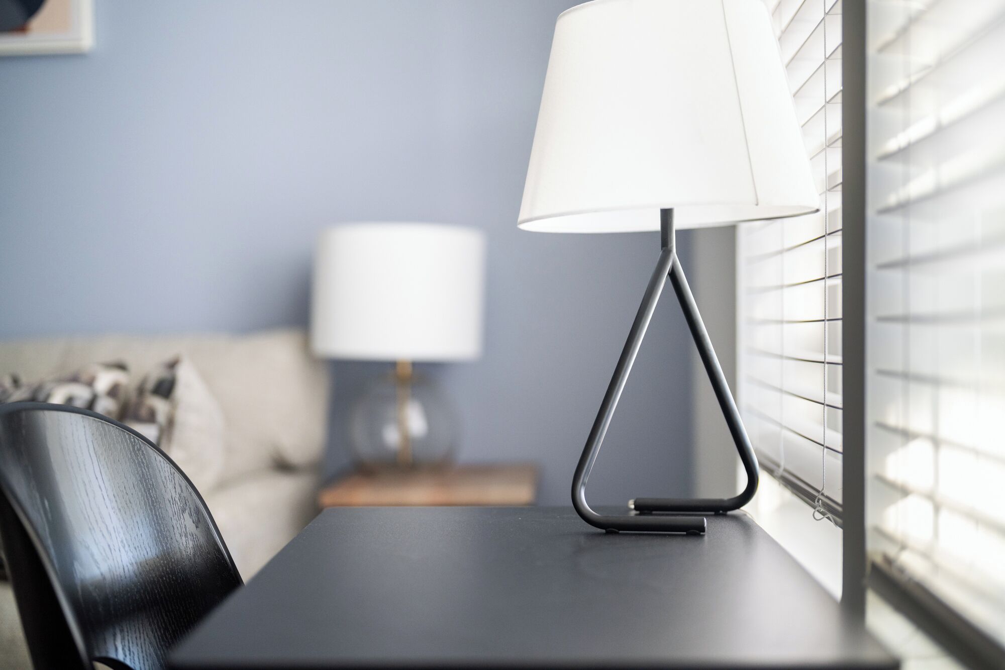 A modern room with a table, a lamp, and a window with blinds.