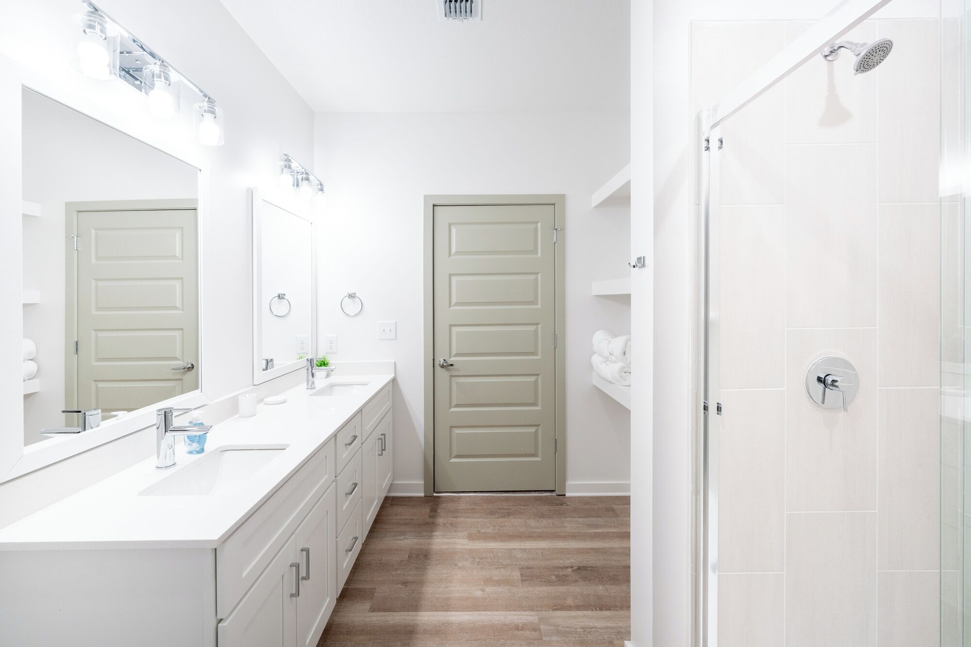 Une salle de bain moderne avec un meuble-lavabo blanc, un grand miroir et un espace douche.