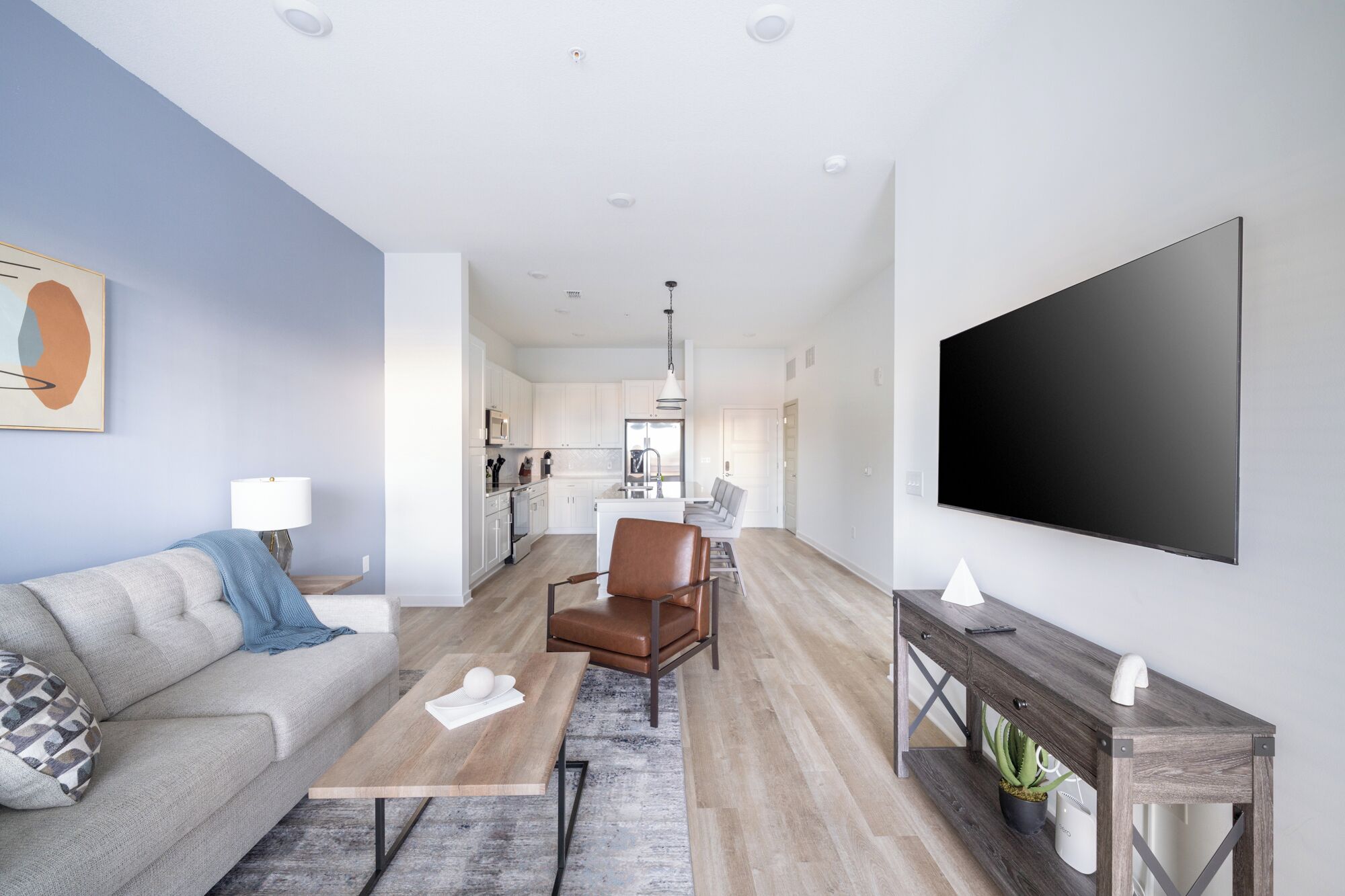 A modern living room with a sofa, coffee table, and a TV mounted on the wall.