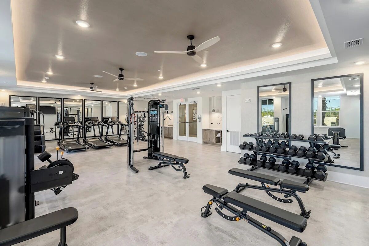 A gym with treadmills, weight benches, and dumbbells.
