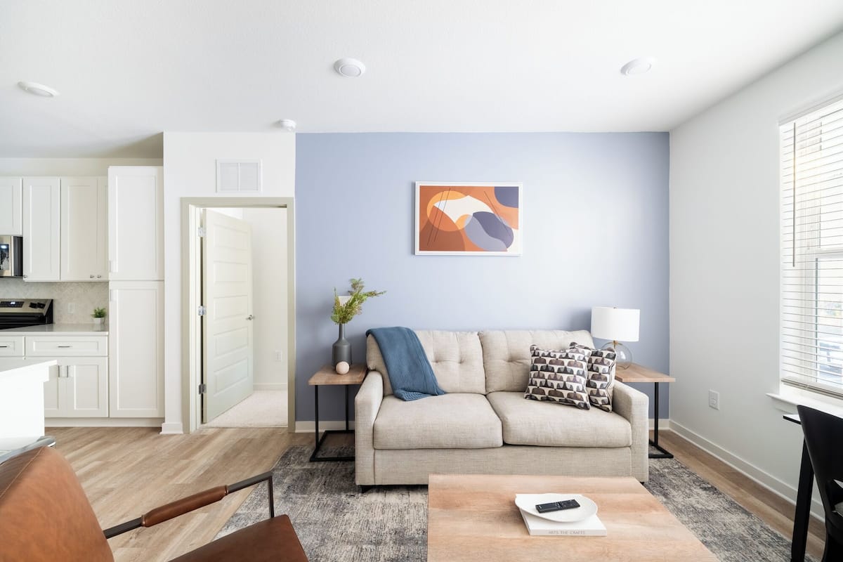 A modern living room with a sofa, coffee table, and a painting on the wall.