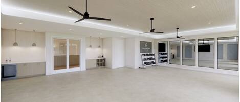 A spacious room with ceiling fans, a shoe rack, and a large mirror.