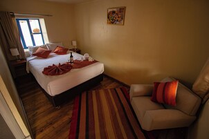 Una habitación de hotel con cama, una silla, una mesita de noche y una ventana con cortinas.