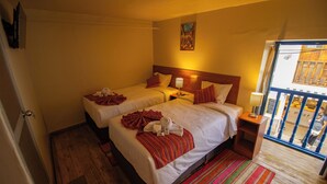 A hotel room with two beds, a wooden floor, a colorful striped rug, and a painting on the wall. - Encanto San Blas (Cusco)