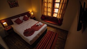 A neatly made bed with pillows, a bedside lamp, and a window with curtains. - Encanto San Blas (Cusco)