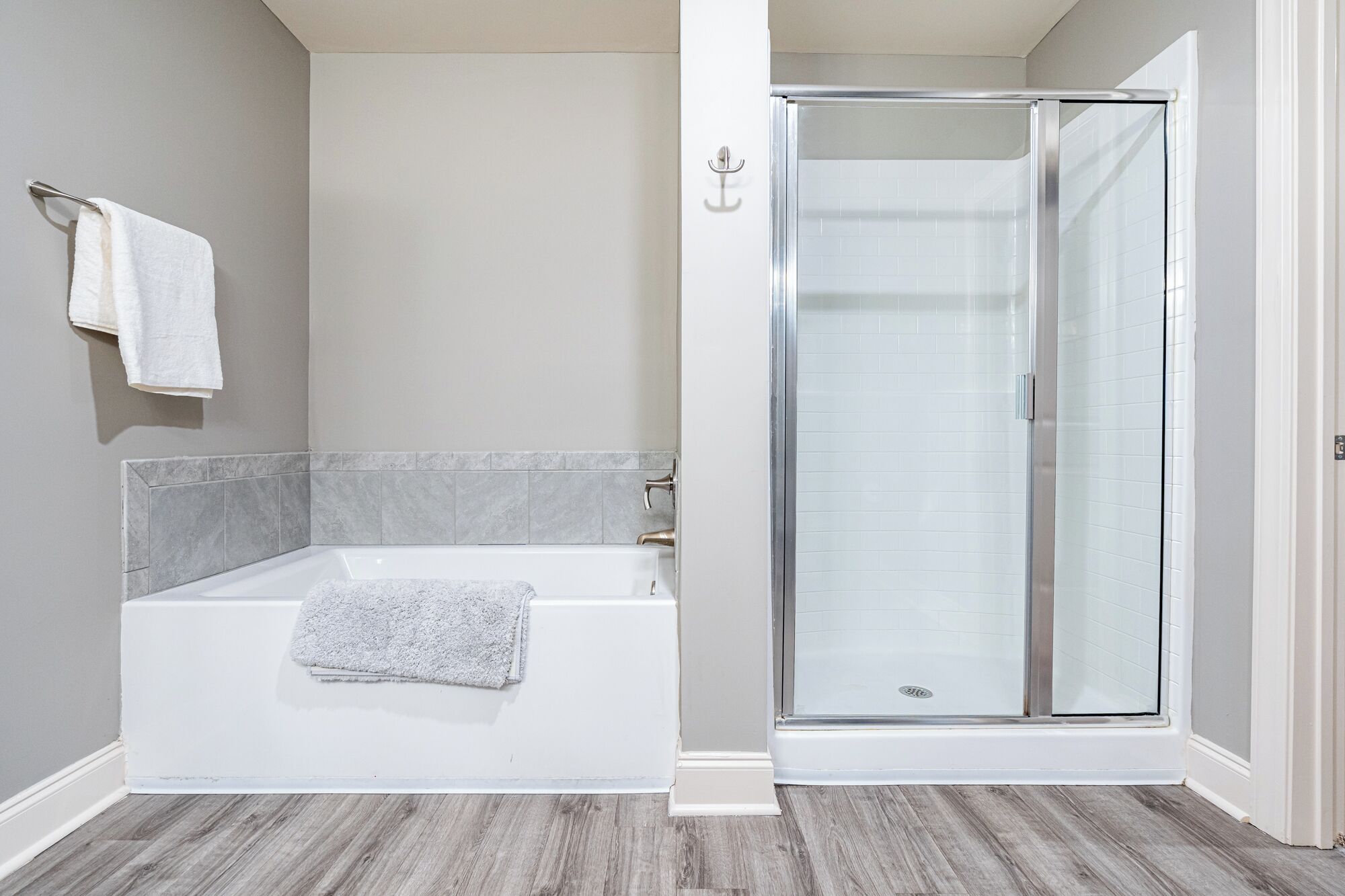 A modern bathroom with a bathtub, a glass shower enclosure, and a towel rack.