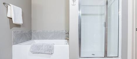 A modern bathroom with a bathtub, a glass shower enclosure, and a towel rack.