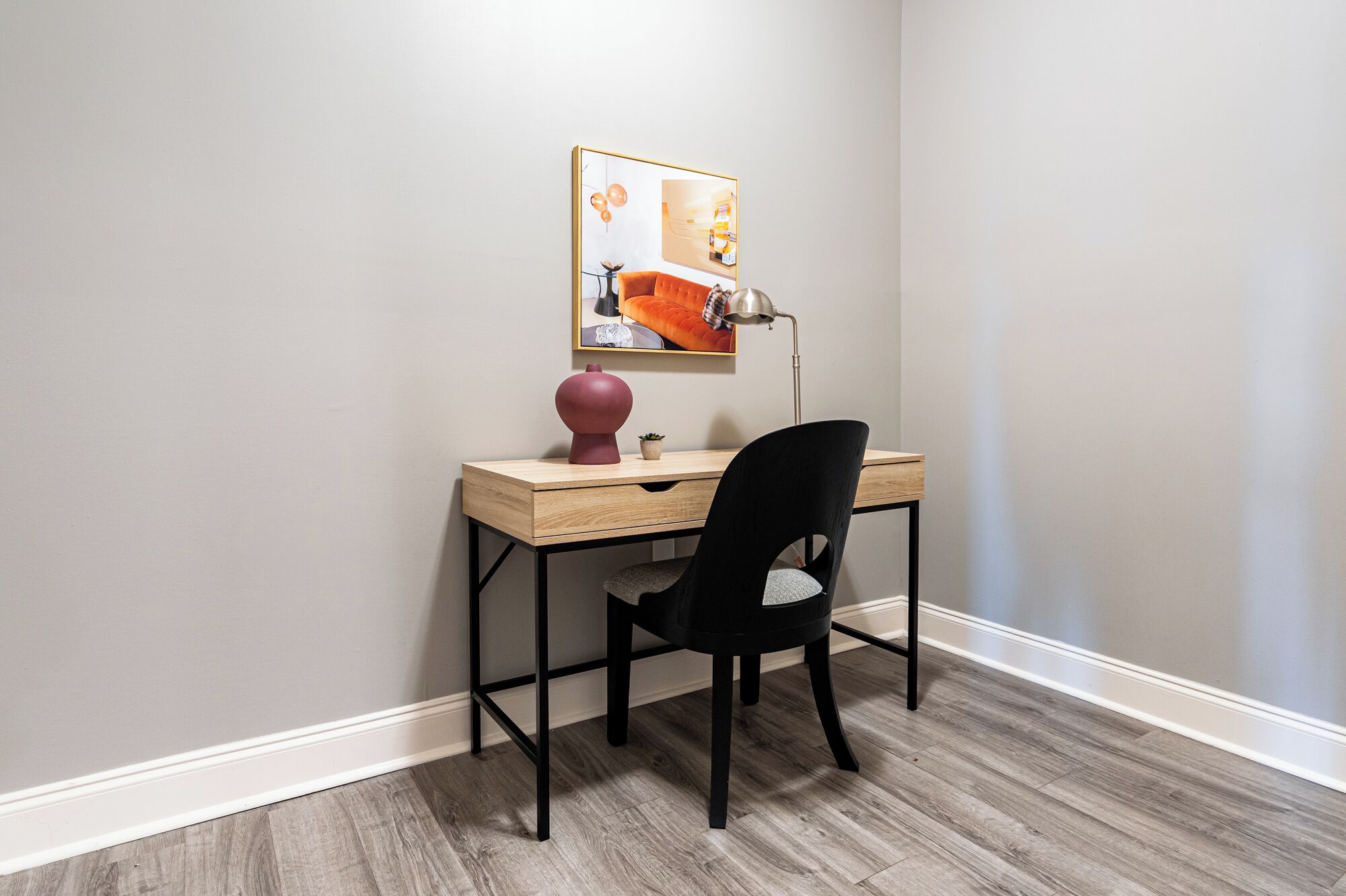 A small, neatly arranged workspace with a desk, chair, and a lamp.