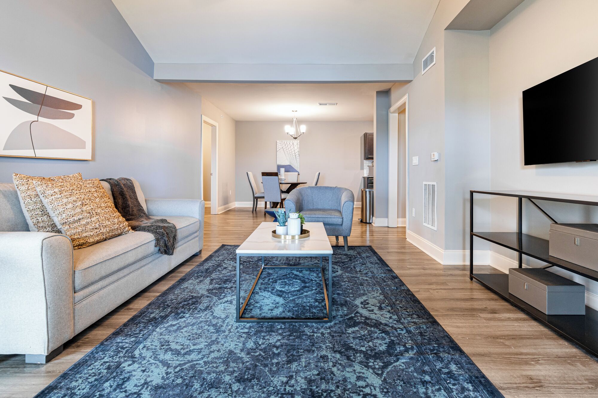 Un salon moderne avec un canapé, une table basse et un téléviseur fixé au mur.