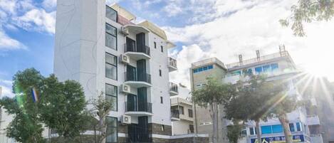 Un immeuble à plusieurs étages doté de balcons, d’une entrée sécurisée et surplombant un ciel dégagé.