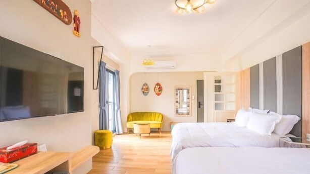 A hotel room with a bed, a TV, a desk, a chair, and a wardrobe. - GREEN LANE B&B (Hualien)