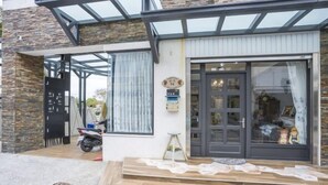 A modern house with a stone facade, a garage door, and a large sliding glass door leading to a covered porch. - GREEN LANE B&B (Hualien)