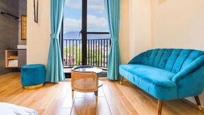 A room with a sofa, a chair, a small table, and a view through a window. - GREEN LANE B&B (Hualien)