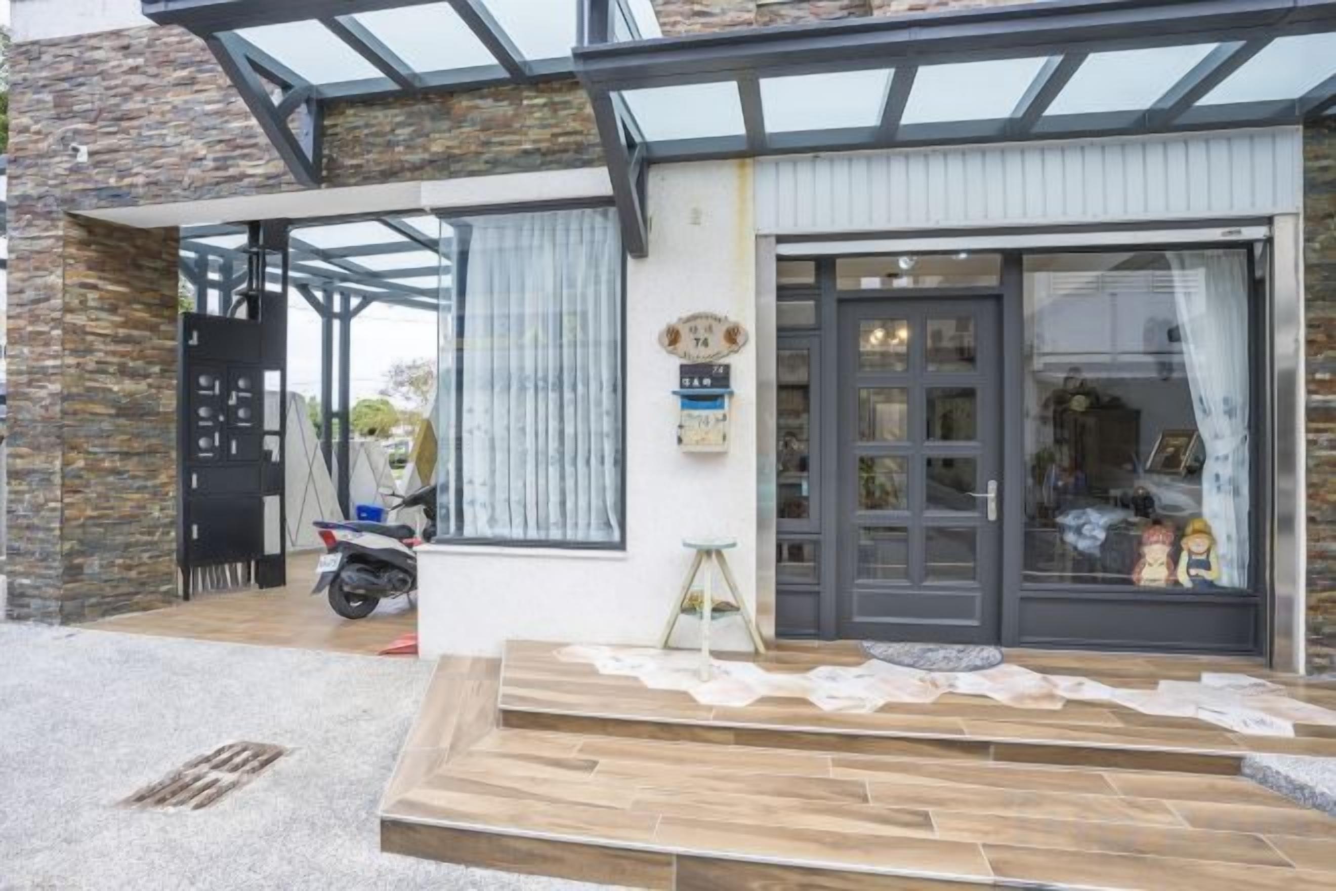 A modern building with a large glass door, a stone facade, and a wooden deck.