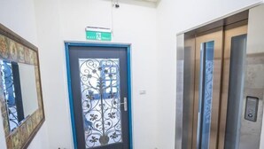 A hallway with a blue door, an elevator, and a fire extinguisher. - GREEN LANE B&B (Hualien)