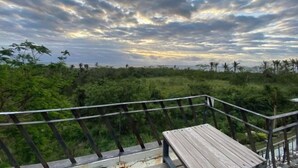 Eine Holzterrasse mit Metallgeländer, das auf eine üppige grüne Landschaft blickt.