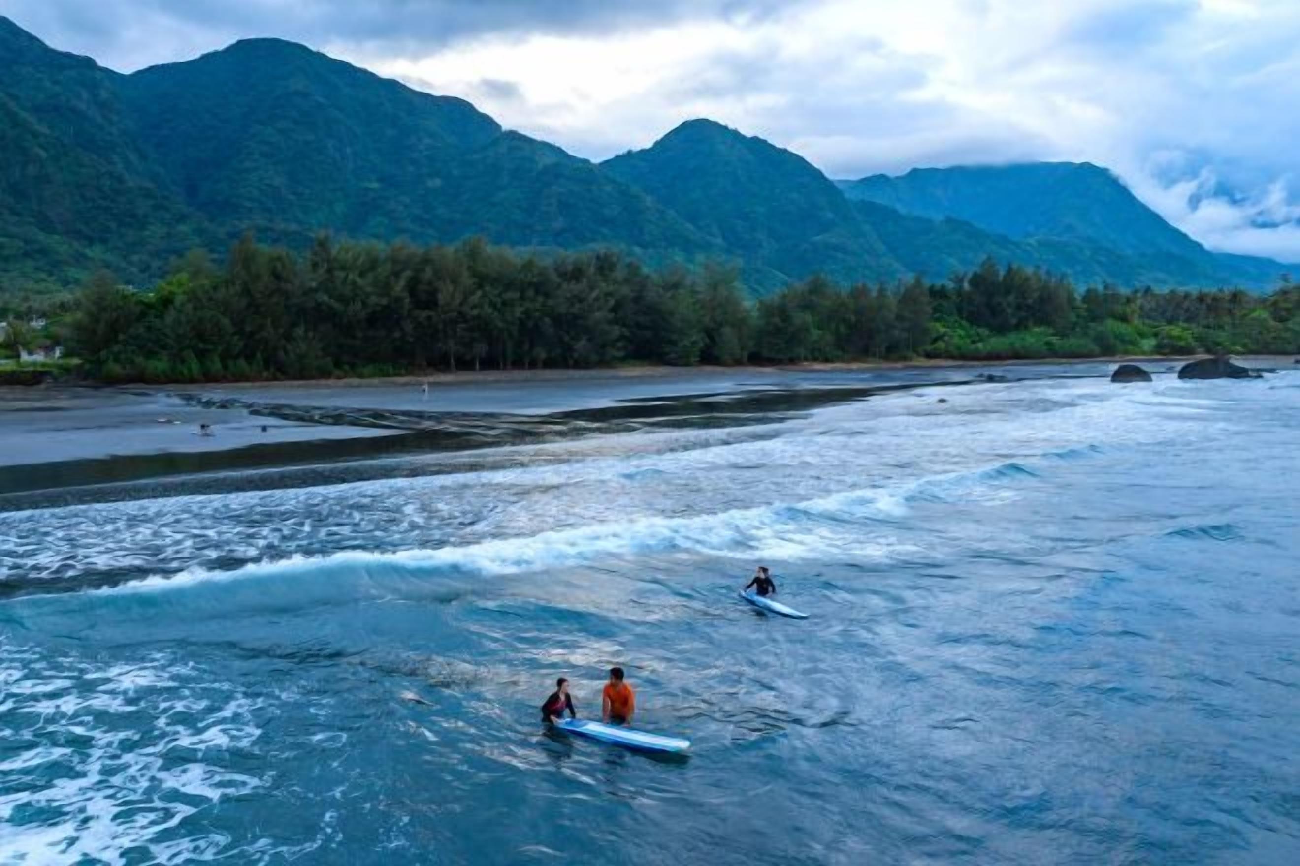 A river with kayaks, surrounded by mountains and trees.