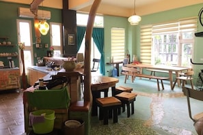Un comedor acogedor con mesas y bancos de madera, una zona de cocina con mostrador, y un ventanal que ofrece luz natural.