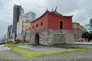 A traditional building with a red facade and a stone base, surrounded by modern high-rise buildings. - Ximen Relite Hotel (Taipei)