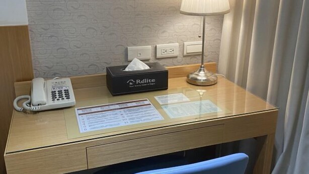 A hotel desk with a telephone, a tissue box, a lamp, and informational cards. - Ximen Relite Hotel (Taipei)