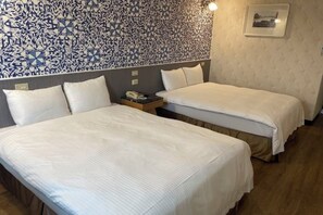 Une chambre d’hôtel avec deux lits, un mur décoré de motifs, un tableau encadré et une table de chevet avec un téléphone.