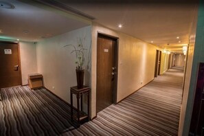 Ein Hotelgang mit Teppichböden, Holztüren und einem Blumentopf.