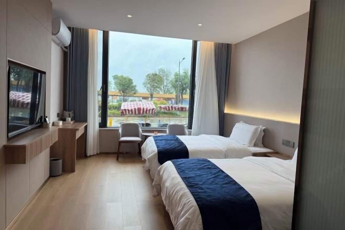 Une chambre d’hôtel avec deux lits, un bureau, une chaise et un téléviseur.