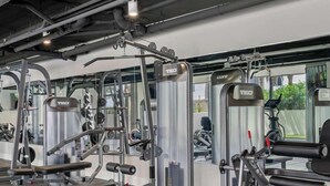 A gym with various exercise machines, including weight benches and cable machines.