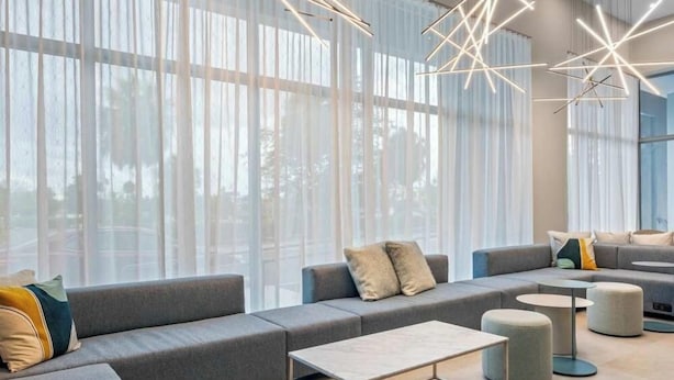 A modern lounge area with a grey sectional sofa, round ottomans, and a coffee table.