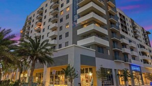 A multi-story hotel with balconies, a ground-level entrance, and a visible fire hydrant.