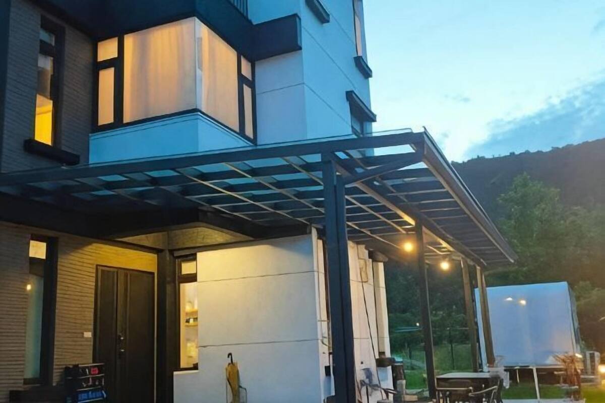 Een modern huis met twee verdiepingen, een overdekte patio, een garage en een zichtbare oprit.