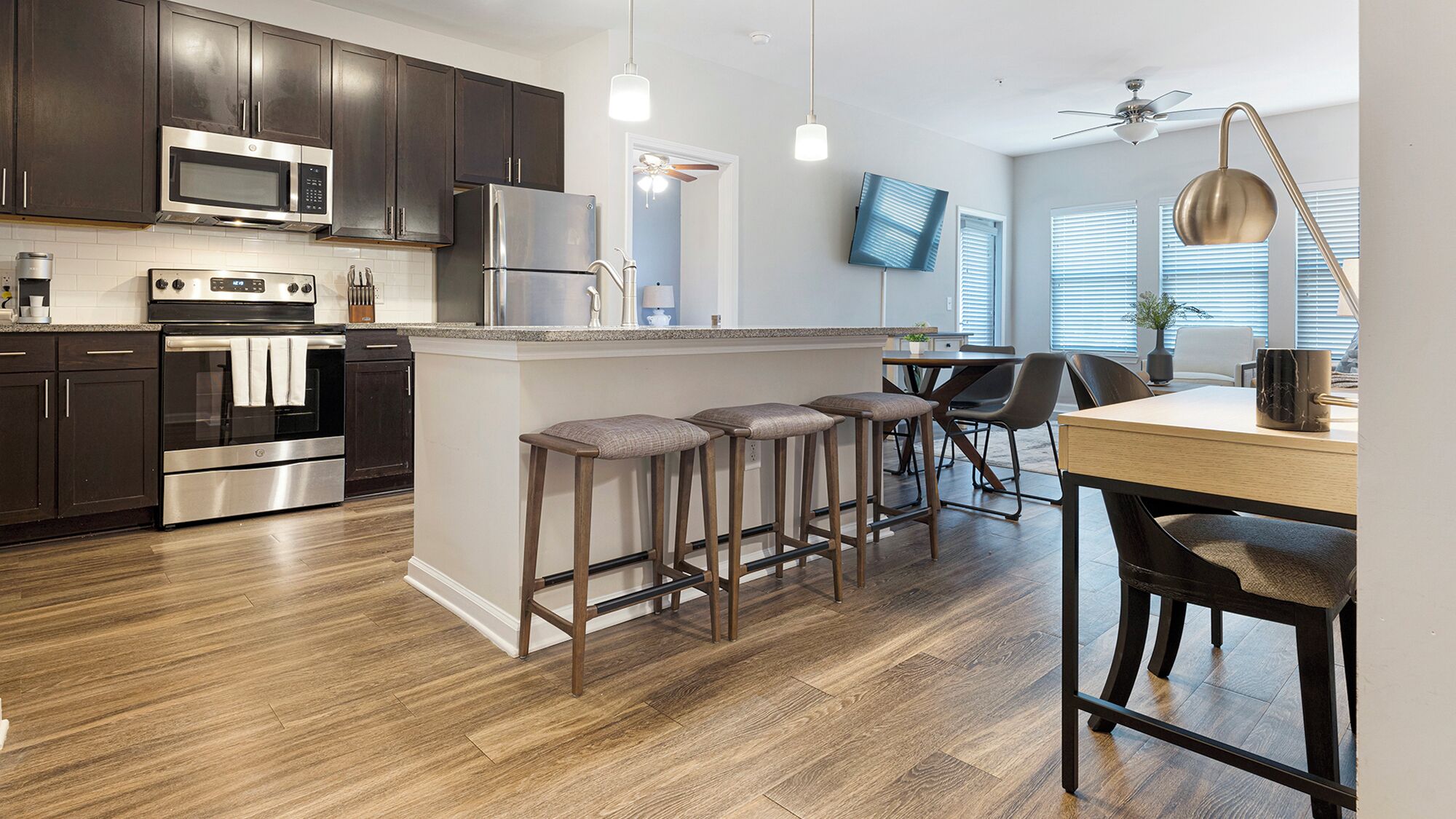 A modern kitchen with dark cabinets, stainless steel appliances, and a central island with bar stools.
