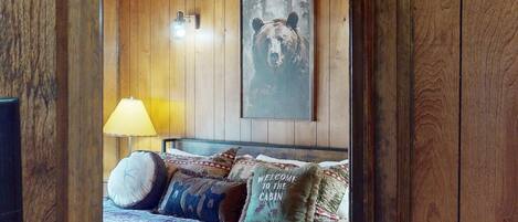 L’intérieur d’un chalet en bois, avec un lit, une lampe et une décoration murale sur le thème des ours.