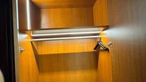 Un placard en bois avec une tringle en métal et un cintre noir.