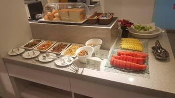 Buffet-pöytä, jossa on tarjolla monenlaista ruokaa ja ruokailuvälineitä.