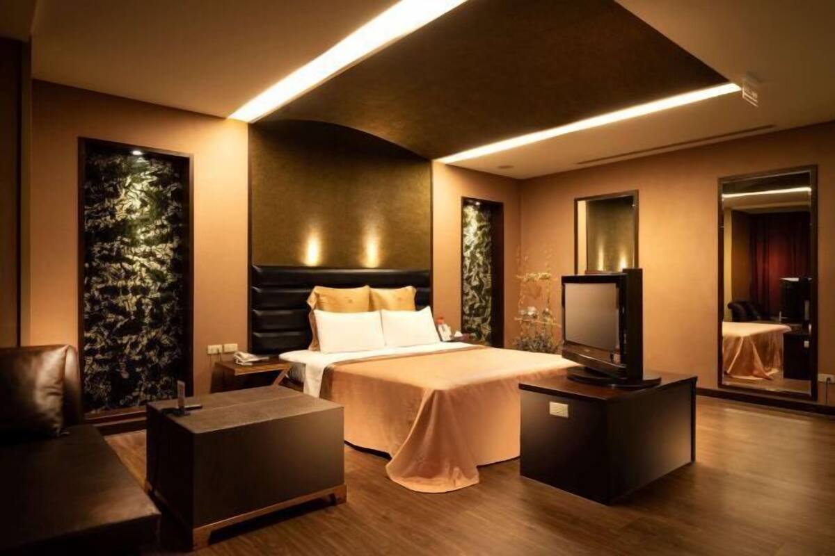 Une chambre d’hôtel moderne équipée d’un lit, d’un bureau, d’une chaise, d’une télévision et d’un miroir.