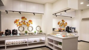 A modern kitchen with white cabinetry, a central island with a coffee machine, and decorative wall art. - Only Love Motel (New Taipei City)