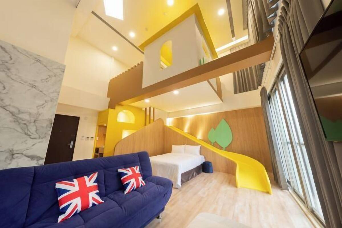 Une chambre d’hôtel moderne avec un canapé bleu, un lit, un escalier en bois et un mur en marbre.