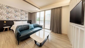 A modern hotel room with a leather sofa, a glass coffee table, a large TV, and a patterned wallpaper. - Only Love Motel (New Taipei City)