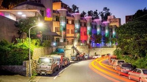 A multi-story hotel with a modern design, featuring a mix of glass and concrete facades, and a parking area with several vehicles. - Only Love Motel (New Taipei City)