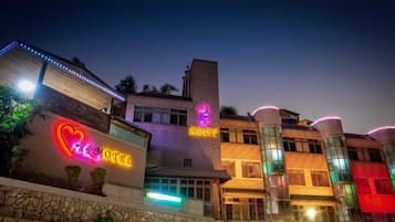 A hotel with a neon sign, a stone facade, and a modern design.