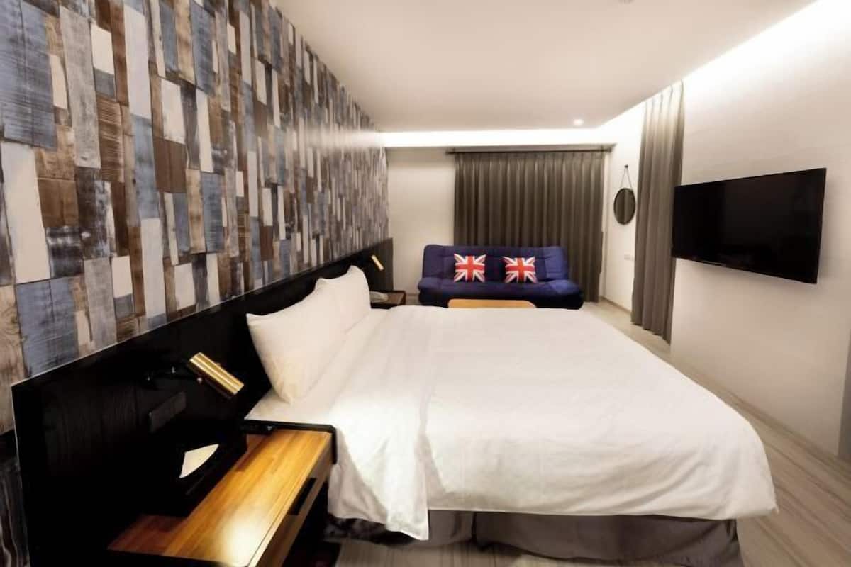 Une chambre d’hôtel avec un grand lit, une tête de lit en bois, un téléviseur à écran plat et un mur orné d’un motif texturé.