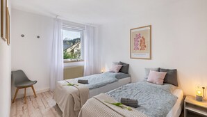 A bedroom with two beds, a chair, a nightstand, and a window with a view. - AlbGlück 2, Hechingen, 1–7 people, castle 5 km away (Hechingen)