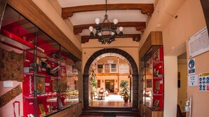 Una hall d'albergo con travi in legno, un lampadario e un tappeto rosso con la scritta 'HOTEL CAJAMARCA'.