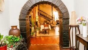 Un ingresso con arco in pietra che conduce a una scalinata e a un'area relax con tavolo e sedie.